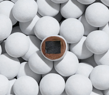 Load image into Gallery viewer, A close-up top-down view of many white spherical objects, with one central sphere showing a brown circular base and a dark square patch on top. Lakrids by Bulow Frozen Mint Licorice.