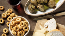 Load image into Gallery viewer, De Carlo grilled artichokes with extra virgin olive oil, served as antipasti along with tarallini crackers and cheese.  Set on wood table, with glass of wine.
