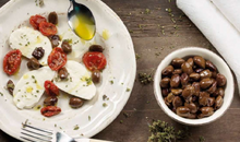 Load image into Gallery viewer, Blowl of De Carlo Pitted "Leccina" Olives in Oil, Alongside Plate of Fresh Mozzarella, Sun-Kissed Tomatoes and Oregano, on a Wood Table