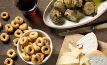 Load image into Gallery viewer, De Carlo tarallini crackers, grilled artichokes and cheese on board, on table with glass of wine.