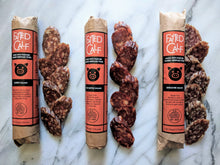 Load image into Gallery viewer, Whole salami next to sliced of Fatted Calf single breed salamis.