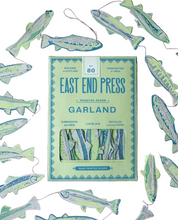 Load image into Gallery viewer, East End Press Garland book cover shown on a dark wood surface, surrounded by hanging fish-shaped paper garlands. The cover reads 'EAST END PRESS GARLAND' and shows a window with layered fish illustrations.
