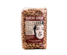 Load image into Gallery viewer, A clear plastic bag of Rancho Gordo Cranberry Bean chili powder stands on a burlap cloth on a wooden surface, with a rustic, blurred background.
