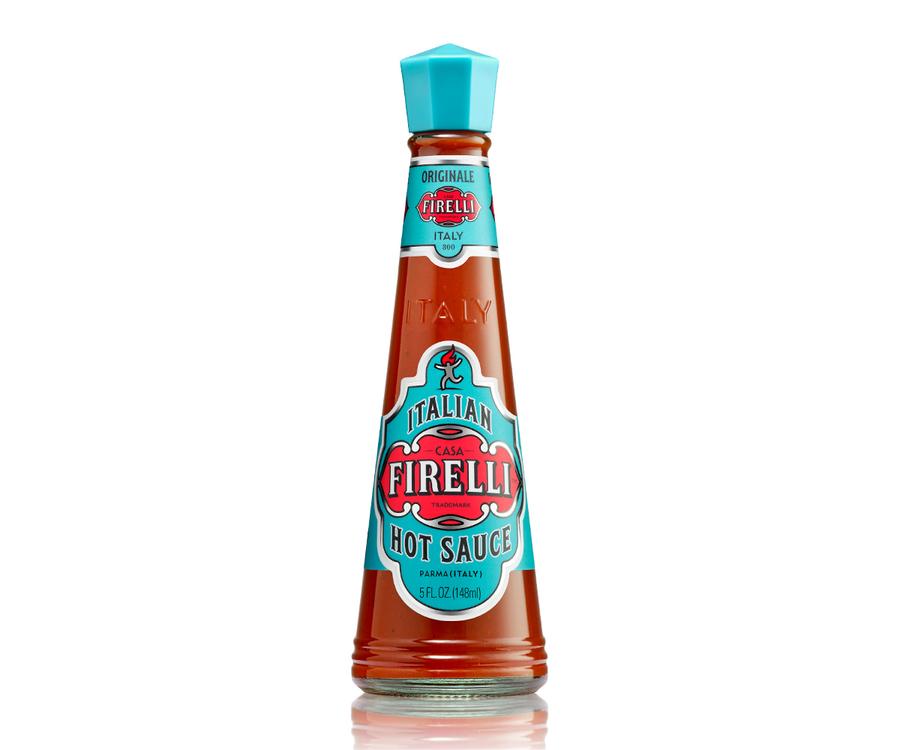 Clear cone shaped glass bottle with teal blue and red lable on white background of Firelli Italian Hot Sauce
